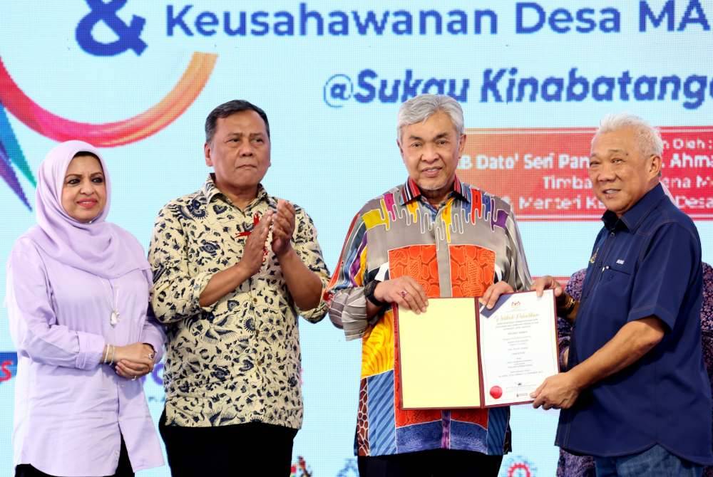 Ahmad Zahid (dua, kanan) menyerahkan watikah pelantikan Jawatankuasa Komuniti Desa Madani kepada Bung Moktar yang mewakili 132 pengerusi dan setiausaha dari 66 kampung. Foto Bernama