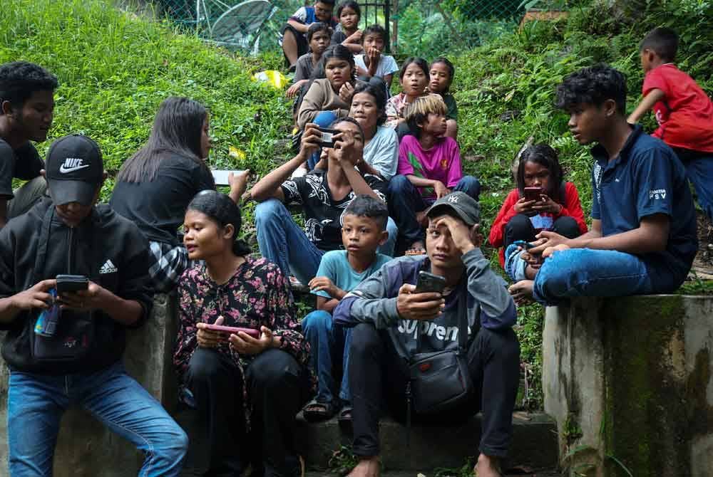 Kanak-kanak dan remaja Kampung Orang Asli, Kerling leka bersama telefon pintar masing-masing yang telah mendapat sambungan internet. Foto Bernama
