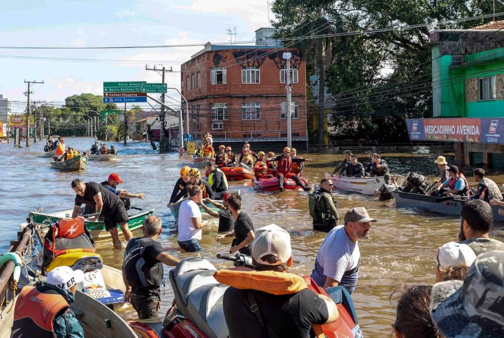 Mangsa banjir dipindahkan menggunakan bot ke tempat perlindungan sementara.