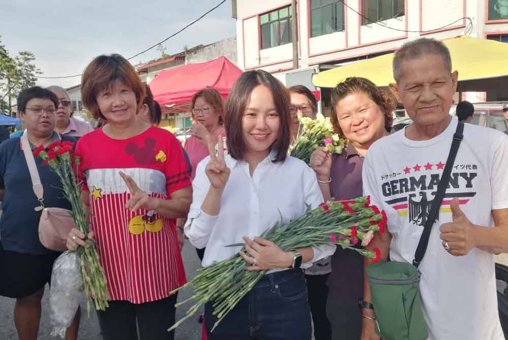 Sock Tao (tengah) bergambar bersama penduduk setempat semasa program edaran bunga sekitar Pekan Rasa pada Ahad.