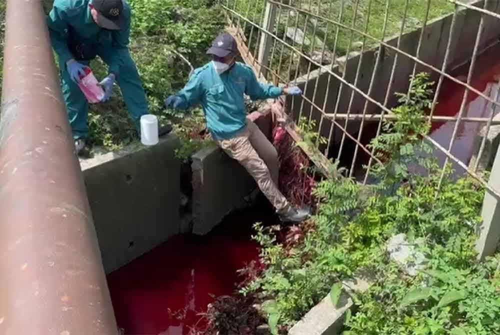 Anggota penguat kuasa JAS mengambil sampel air dari longkang yang dicemari bahan berwarna merah.