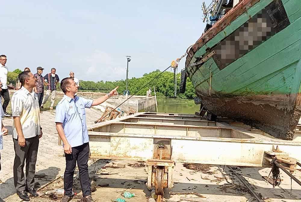 Muhammad Faiz (kanan) melihat bot yang masuk untuk dibaiki di slipway PNK Kuala Kedah, Kampung Teluk Layang pada Isnin.