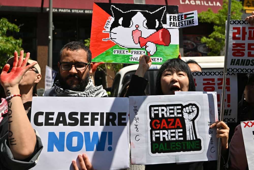 Kumpulan penunjuk perasaan membawa plakad sambil mengutuk rejim Zionis di Seoul.