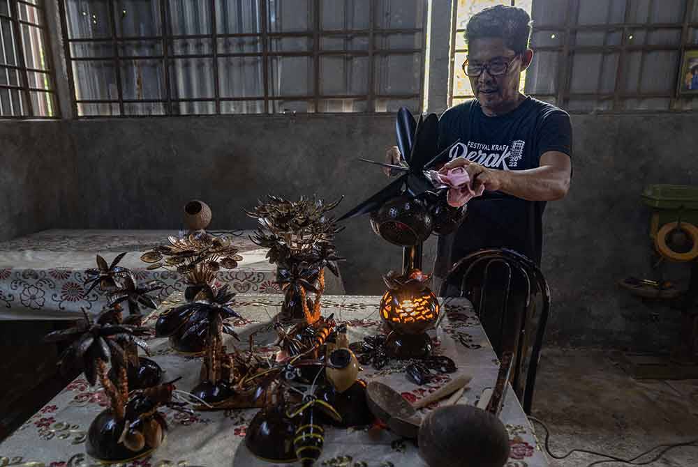 Mad Saril melakukan kerja-kerja mengilap kraf tangan daripada tempurung dan batang kelapa ketika tinjauan di bengkelnya di Kampung Sungai Betul baru-baru ini. Foto Bernama