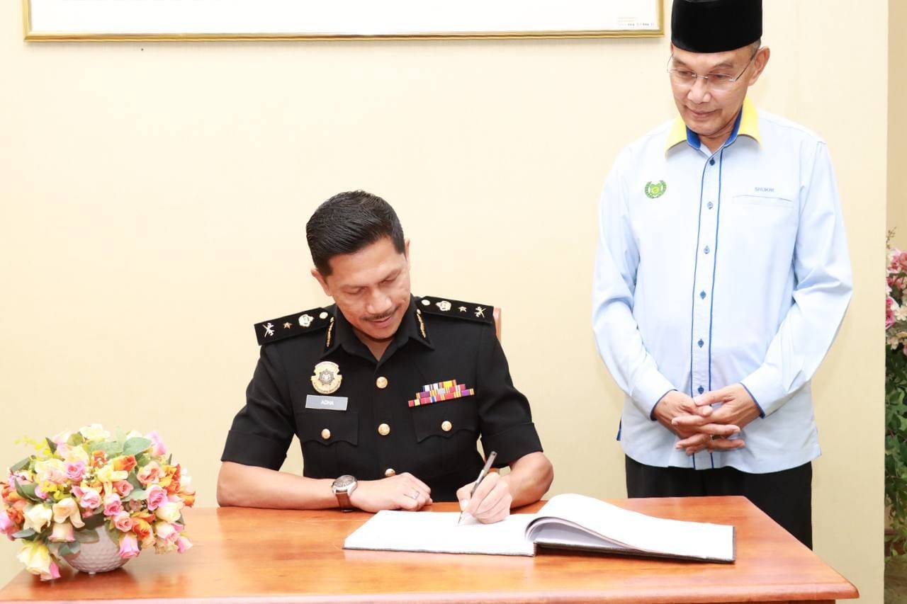 Mohd Nor Adha menandatangani buku pelawat sambil disaksikan Mohd Shukri di pejabat Menteri Besar Perlis.