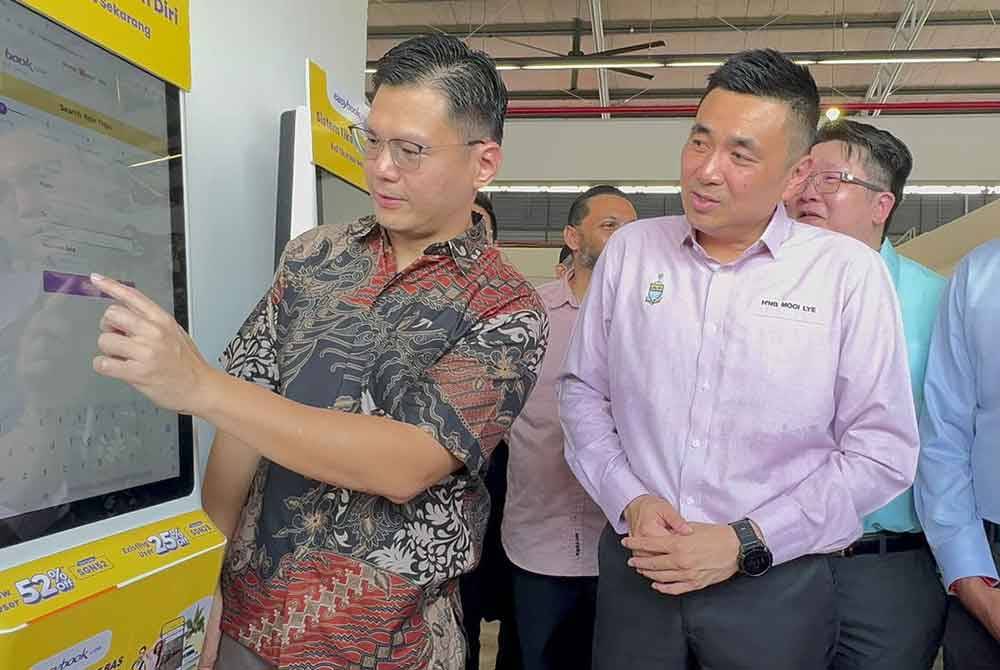 William (kiri) menunjukkan cara mengendalikan kiosk Easybook yang disediakan di TSN kepada Mooi Lye pada Selasa.