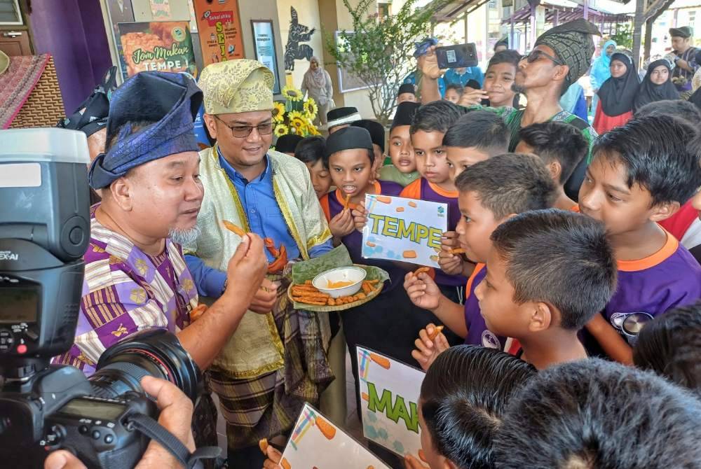 Saiful (dua dari kiri) bersama Mohd Alhamadi (kiri) menunjukkan tempe goreng kepada murid pada program berkenaan di SK Padang Garuda pada Selasa.