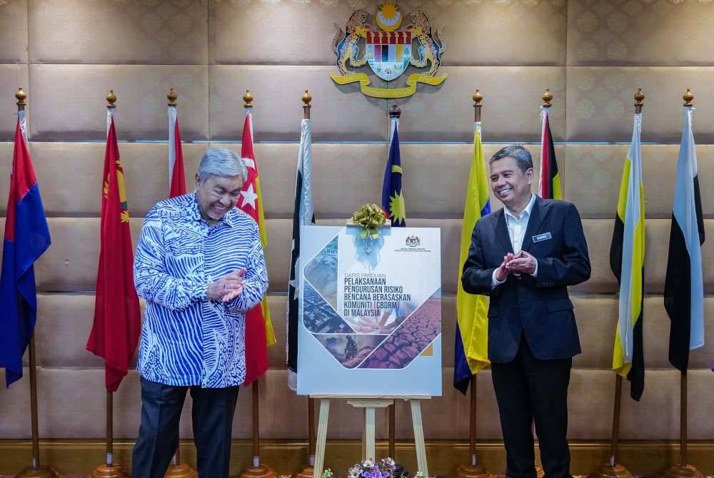Ahmad Zahid (kiri) melancarkan Buku Garis Panduan Pelaksanaan Pengurusan Risiko Bencana Berasaskan Komuniti (CBDRM) di Malaysia disaksikan Ketua Pengarah Nadma, Datuk Khairul Shahril Idrus.