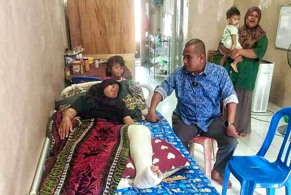 Zahari (duduk) ketika melawat NurulJannah Batrisia Mohd Nazsha,12, yang patah kaki ketika bersukan.