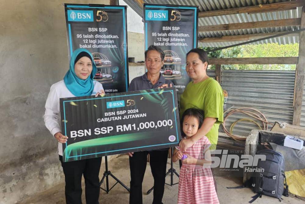 Johni (tengah) bersama isteri dan anak bongsunya menerima replika cek RM1 juta daripada kakitangan BSN selepas menjadi orang ke-99 menang Cabutan Jutawan BSN SSP di Kampung Lasau Minunsud, Kota Belud.