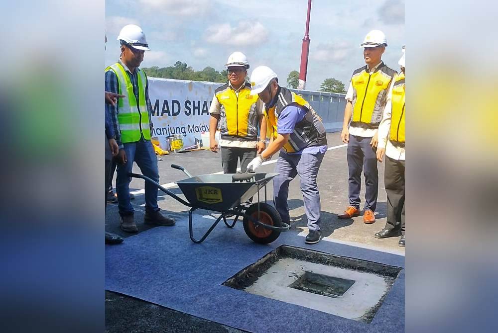 Alexander (tiga dari kiri) melakukan gimik kerja-kerja penyambungan di jambatan itu pada Jumaat.