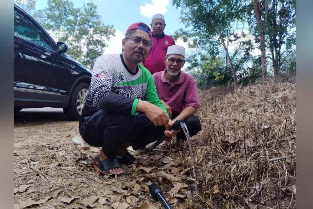 Mohd Husaimi menunjukkan bekalan air yang telah disalurkan melalui sungai berhampiran ke kawasan terjejas.