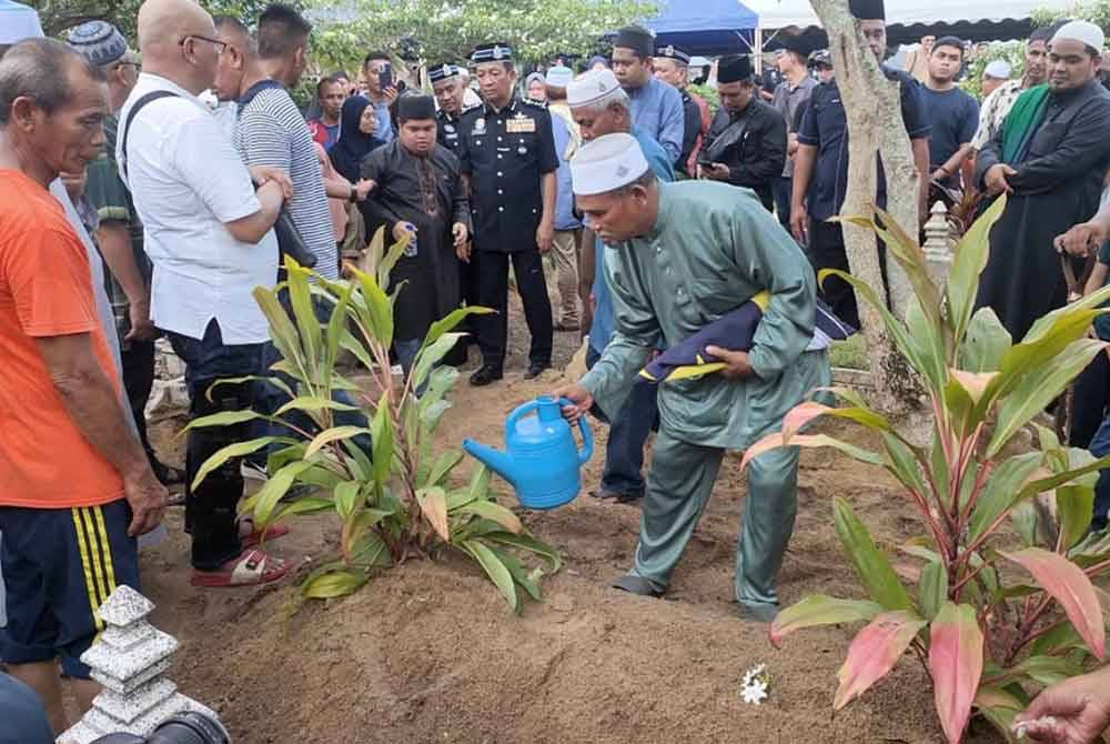 Ahmad Said menyiram air di atas pusara anaknya Allahyarham Muhamad Syafiq di Tanah Perkuburan Islam Batu 8, Jalan Gambang, pada Sabtu.
