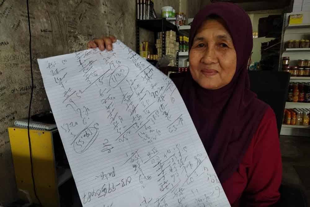 Asmah menunjukkan kiraannya menggunakan pensel di atas kertas.
