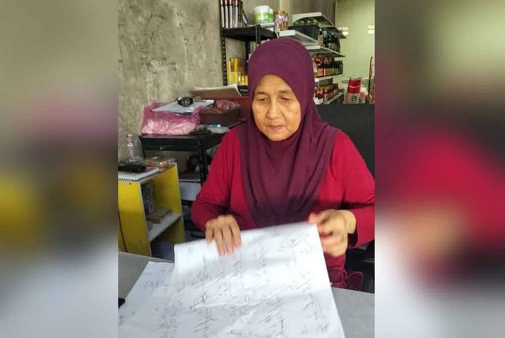 Asmah membelek kertas yang digunakan untuk mengira pempelian pelanggan