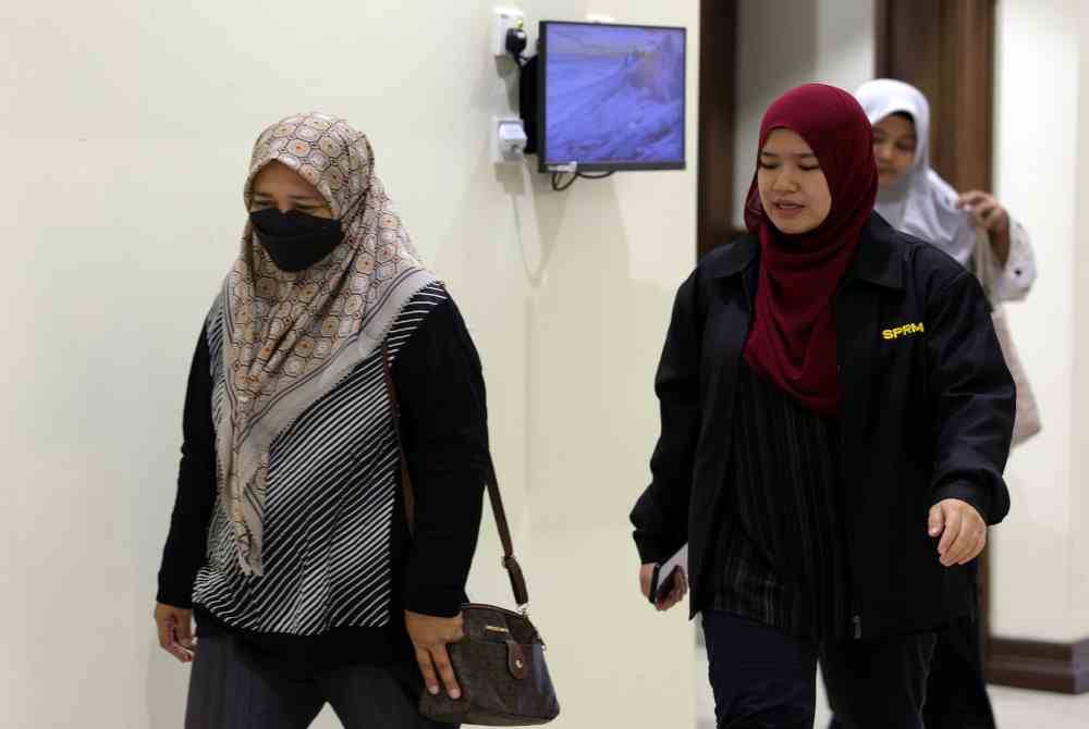 Rasnah (kiri) diiringi pegawai SPRM selepas dihadapkan ke Mahkamah Sesyen Kota Kinabalu pada Selasa. Foto Bernama