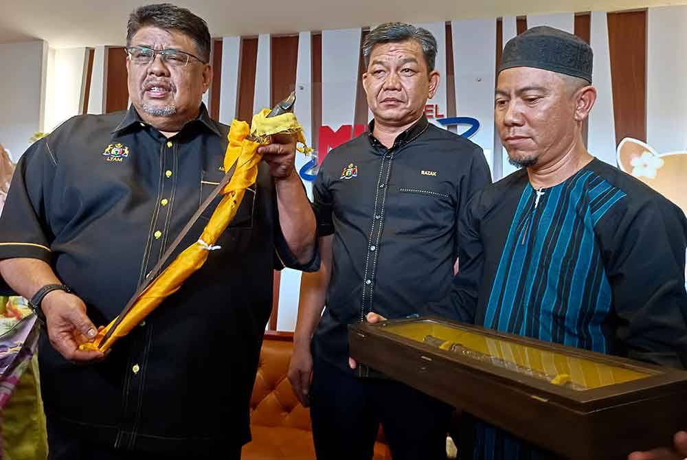 Ketua Menteri Melaka Datuk Seri Ab Rauf Yusoh (kiri) menunjukkan Keris Sundang yang dipercayai kepunyaan Laksamana Hang Tuah yang diserahkan Tun Muhammad Amin Tun Ahmad (kanan) iaitu waris ke-11 Hang Tuah yang berasal dari Kepulauan Bentan Riau Indonesia dalam satu majlis di sini pada Selasa. Foto Bernama