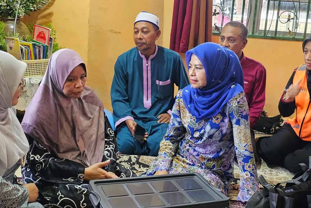 Noraini (tiga dari kanan) menziarahi keluarga Allahyarham Konstabel Ahmad Azza Fahmi di Kampung Poh Tambahan di Bidor.