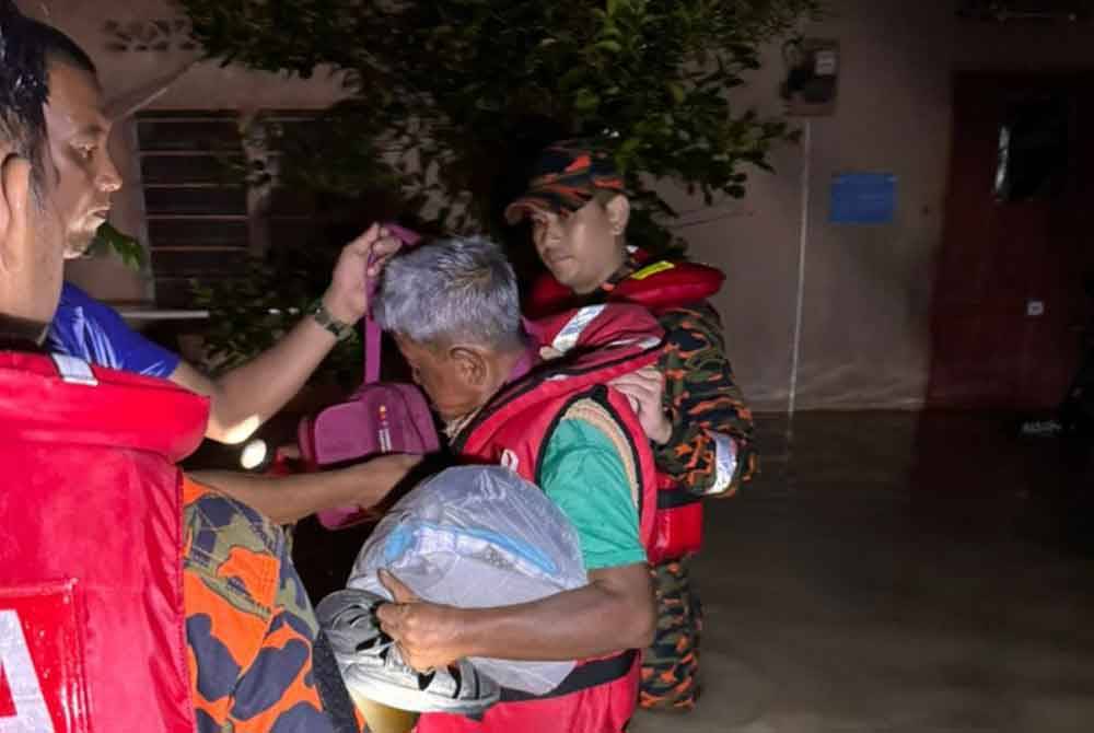 Anggota bomba membantu memindahkan penduduk di Parit selepas rumah mereka dilanda banjir pada Rabu. Foto ihsan Bomba Perak