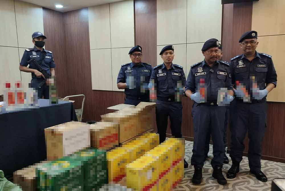 Mohd Asri (depan,kiri) bersama pegawainya menunjukkan sebahagian minuman keras yang dirampas susulan penahanan tiga warga asing di sebuah premis kedai runcit berhampiran tapak pembinaan stesen ECRL di sini pada 10 Mei