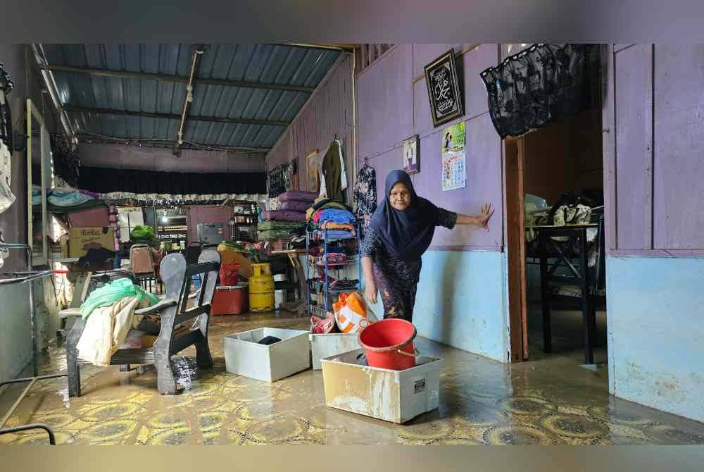 Roziah mengalihkan barang-barang ketika mengemas rumahnya yang dinaiki air pada Rabu.