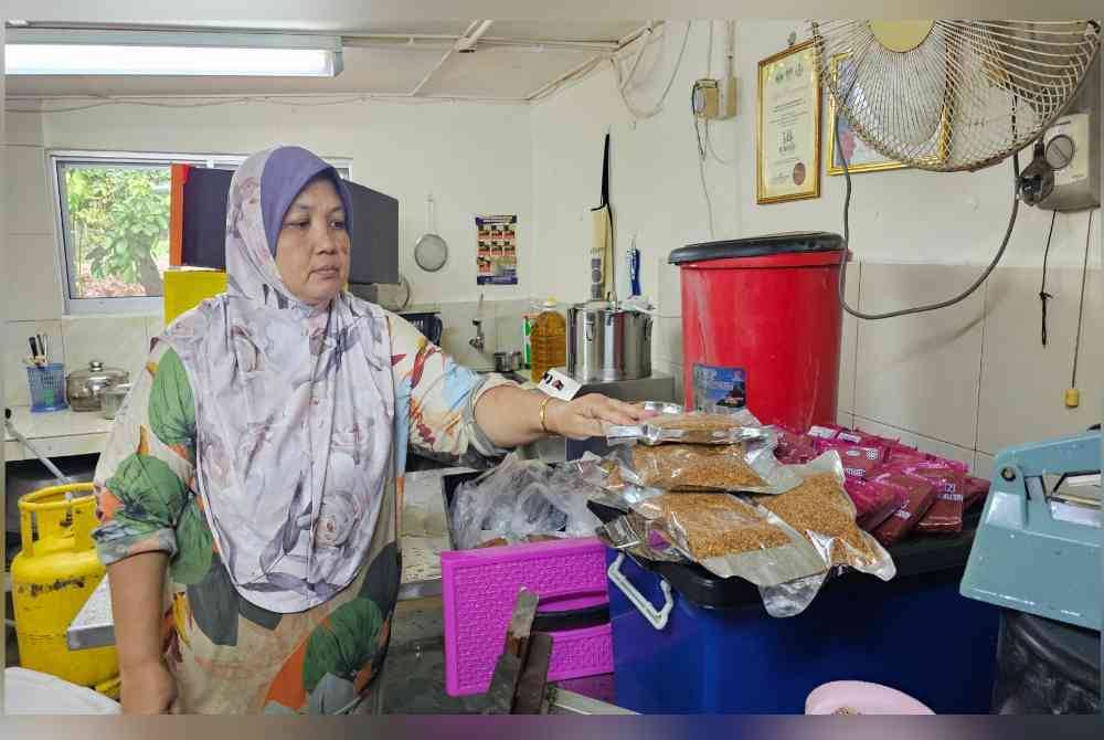 Norlizah menunjukkan produk sambal pecal yang diusahakannya yang rosak ditenggelami banjir di Kampung Serapoh.