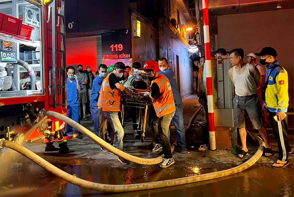 Anggota Bomba dan Penyelamat membawa mangsa ke ambulans berikutan kebakaran besar di blok apartmen di Hanoi. Foto AFP