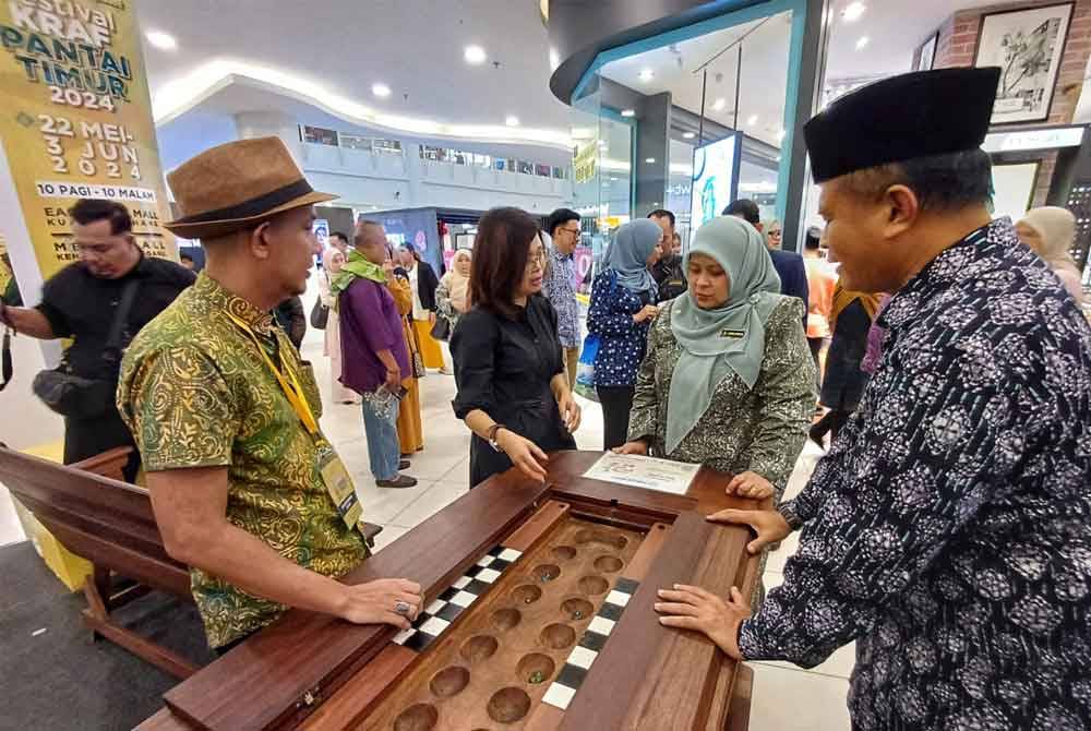 Ainu Sham (tengah) melihat produk kraf berasaskan kayu pada sesi tinjauan mesra FKPT 2024 di sebuah pasaraya di Bandaraya Kuantan di sini pada Jumaat.