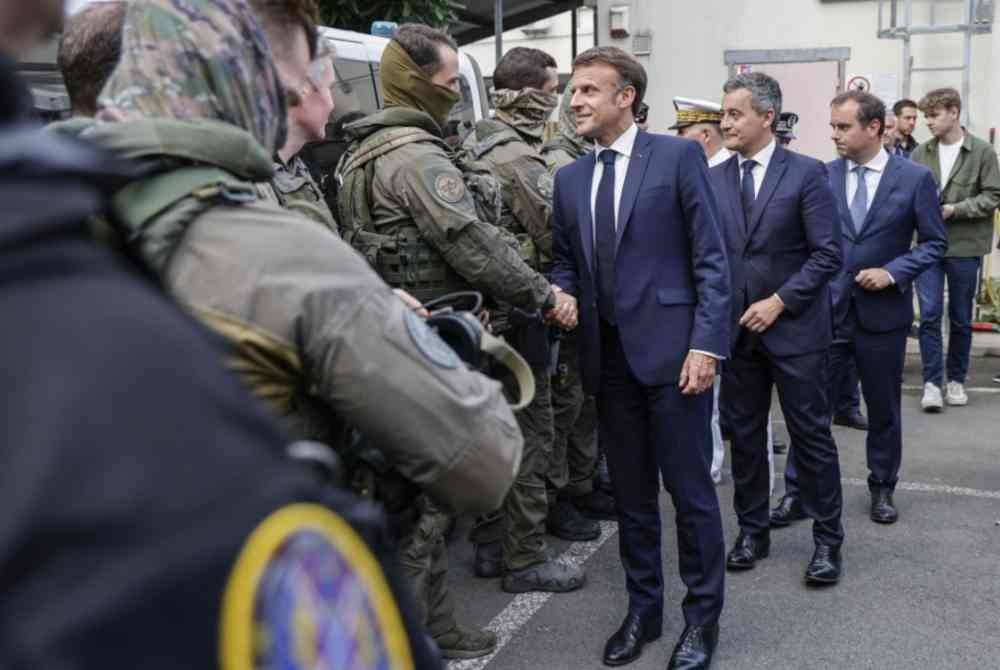 
Macron (hadapan) bersama pengiringnya bertemu anggota keselamatan ketika kunjungan beliau di Noumea pada Khamis.