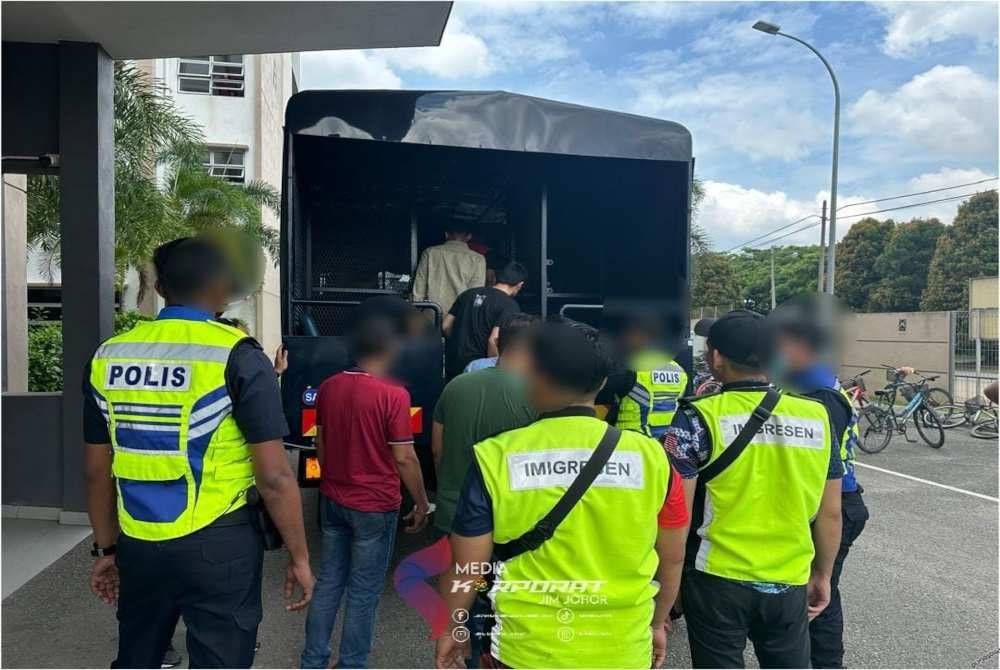 Warga asing yang ditahan dibawa menaiki trak polis. Foto JIM Johor