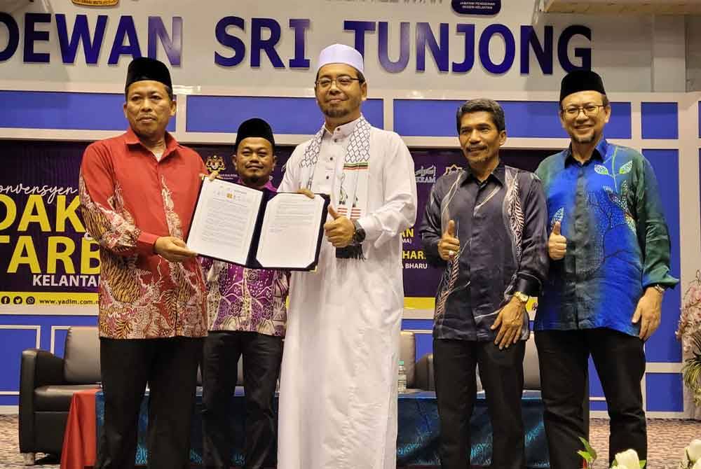 Amir (kiri) menyerahkan Resolusi Konvensyen Dakwah dan Tarbiah Kelantan 2024 kepada Zulkifli (tengah).