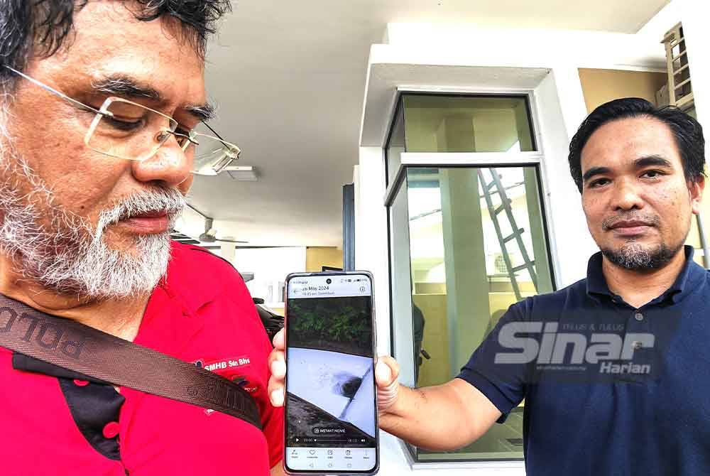 Mohd Khir (kanan) dan Zanifol menunjukkan keadaan air sungai yang mengalir di belakang rumah penduduk.