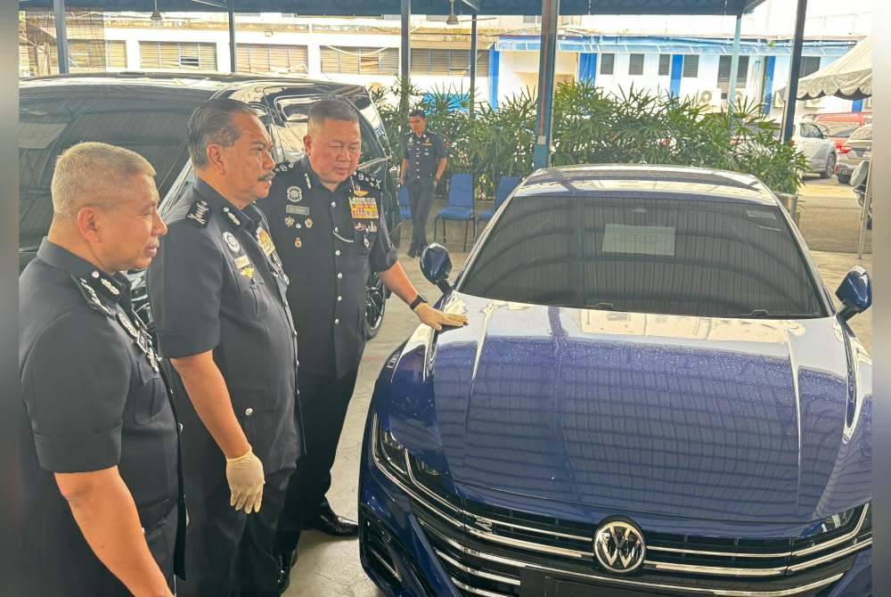 Kok Chin (kanan) menunjukkan kereta yang dirampas daripada suspek.