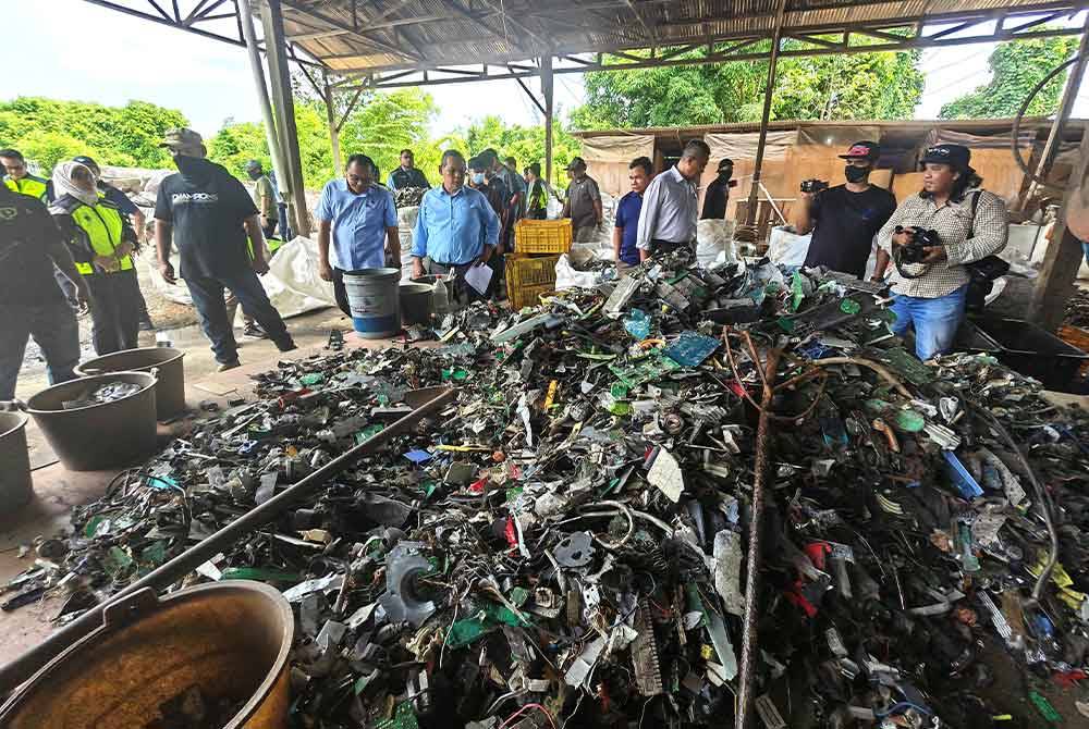 Aminuddin(lima dari kiri) melihat sisa barangan elektrik dan elektronik di sebuah kilang yang diserbu