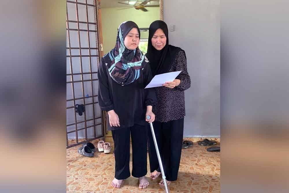 Siti Nur Amalin (kiri) yang menghidap penyakit angin ahmar seluruh badan sejak lima tahun lalu melihat keputusan cemerlang 6A dalam peperiksaan SPM bersama ibunya, Hasmawati Mohamad ketika ditemui di rumahnya di Taman Sri Aman, Kubang Kerian pada Isnin. Foto Bernama