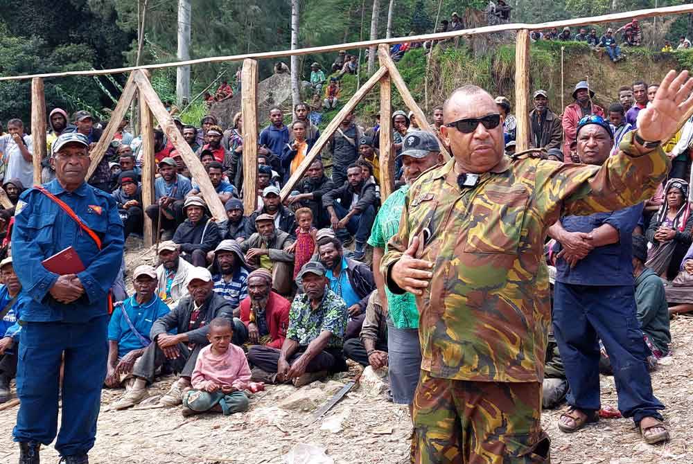 Pegawai Pasukan Pertahanan PNG, Micheal Band memberi taklimat kepada penduduk di perkampungan Mulitaka. - AFP