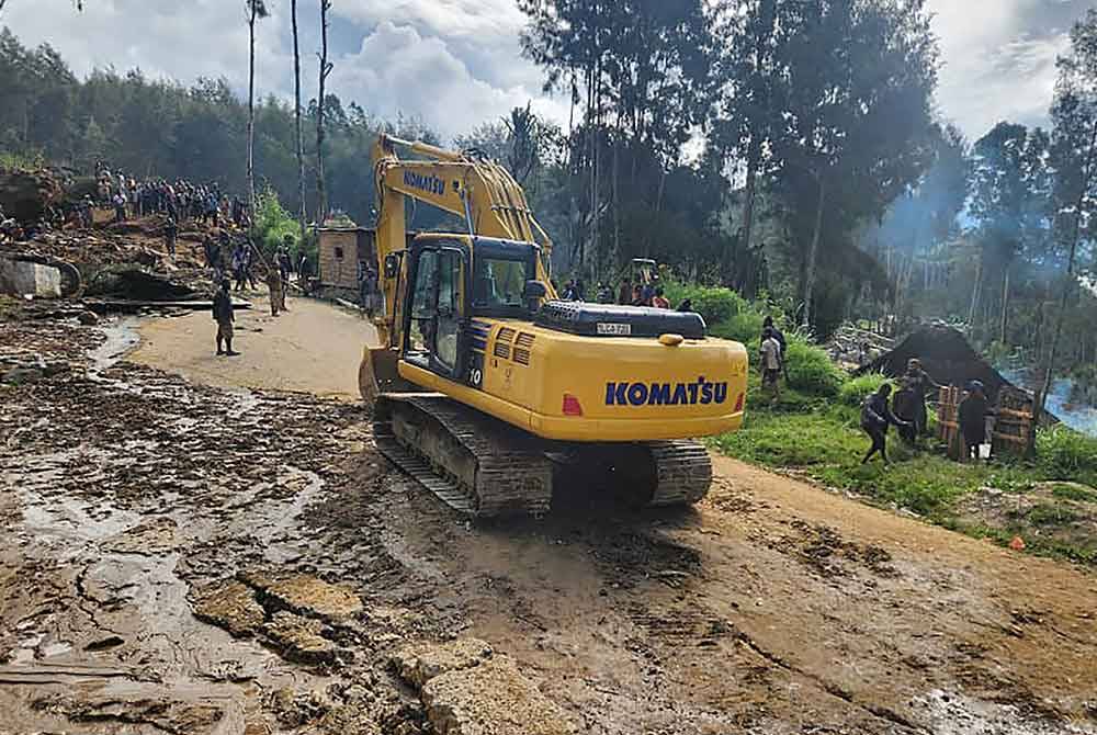 Jentera berat sedang melakukan proses menggali dan memindahkan batu besar yang menghempap perkampungan Yambali di wilayah Enga. - AFP