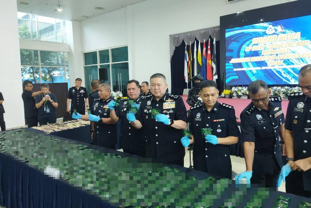 Khaw Kok Chin (tiga kiri) menunjukkan dadah yang dirampas.