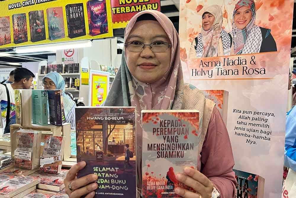 Shahida menunjukkan novel 'Selamat Datang ke Kedai Buku Hyunam-Dong' dan 'Kepada Perempuan Yang Menginginkan Suamiku' yang dijual di reruai Karangkraf sempena PBAKL 2024 di WTCKL.
