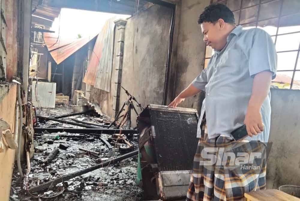 Mohd Shahrulnidzam menunjukkan barang dalam rumahnya yang hangus.