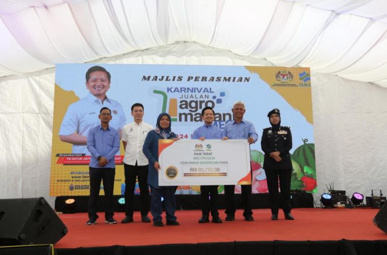 Seorang usahawan FAMA (tiga dari kiri) menerima bantuan menaik taraf produk yang disampaikan oleh Arthur (tiga dari kanan).