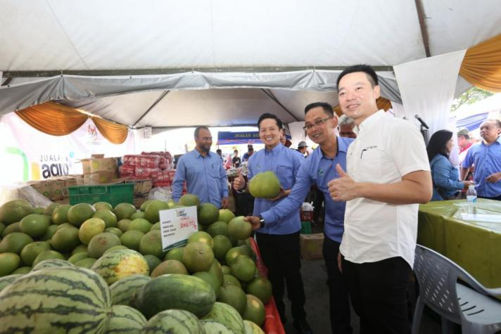 Arthur (tiga dari kanan) menunjukkan buah-buahan segar yang dijual dalam Karnival Jualan Agro MADANI Mega di Tawau, Sabah.