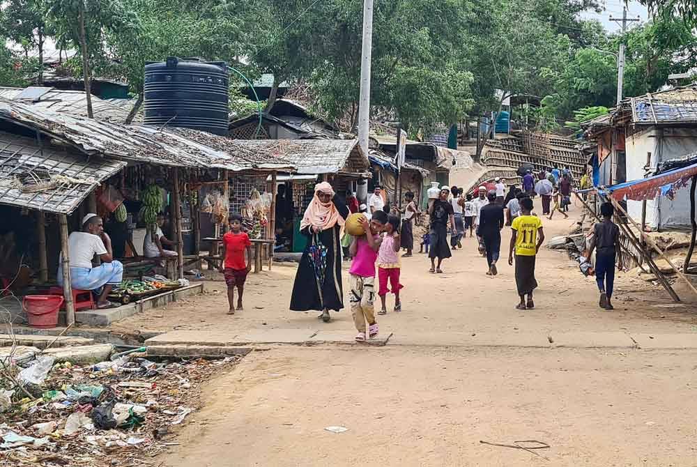 Foto pada 24 Mei lalu menunjukkan pelarian Rohingya berjalan menyusuri laluan di kem mereka di Ukhia di daerah Cox's Bazar, tenggara Bangladesh. - AFP