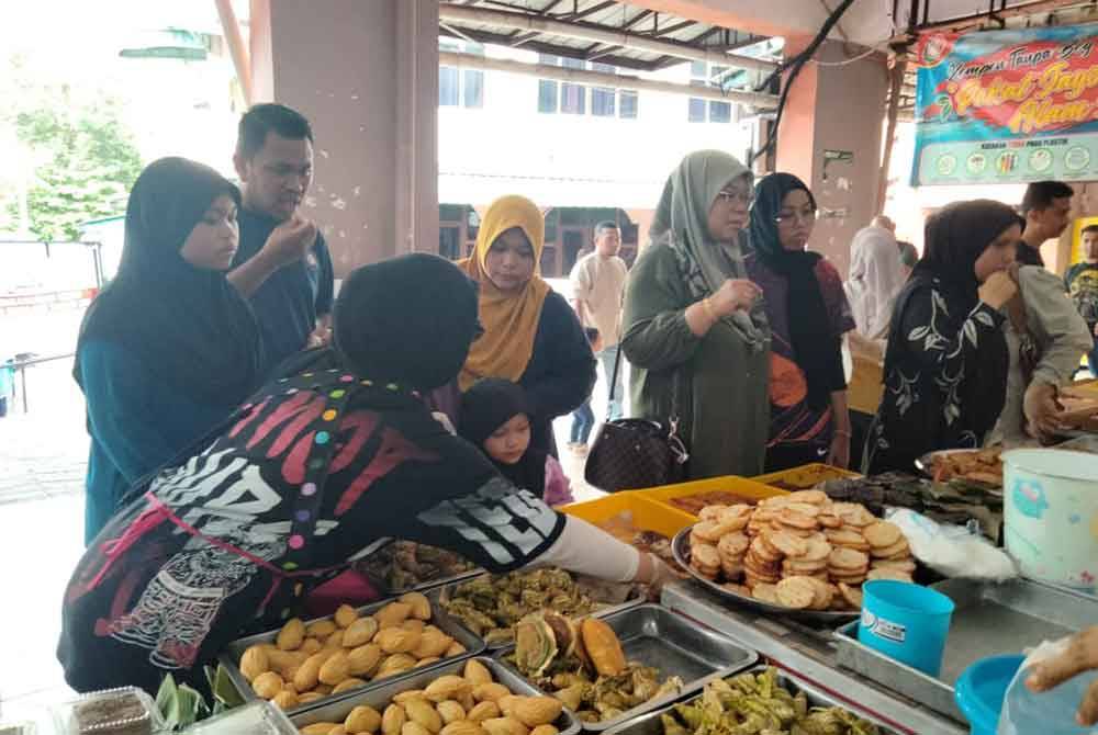 Siti Hawa (tengah) dan keluarga membeli akok di Pasar Siti Khadijah
