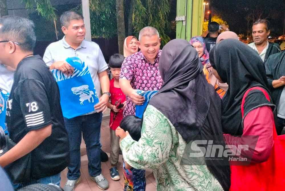 Rais (tengah) menyerahkan cenderamata kepada pengunjung terawal Zoo Melaka.