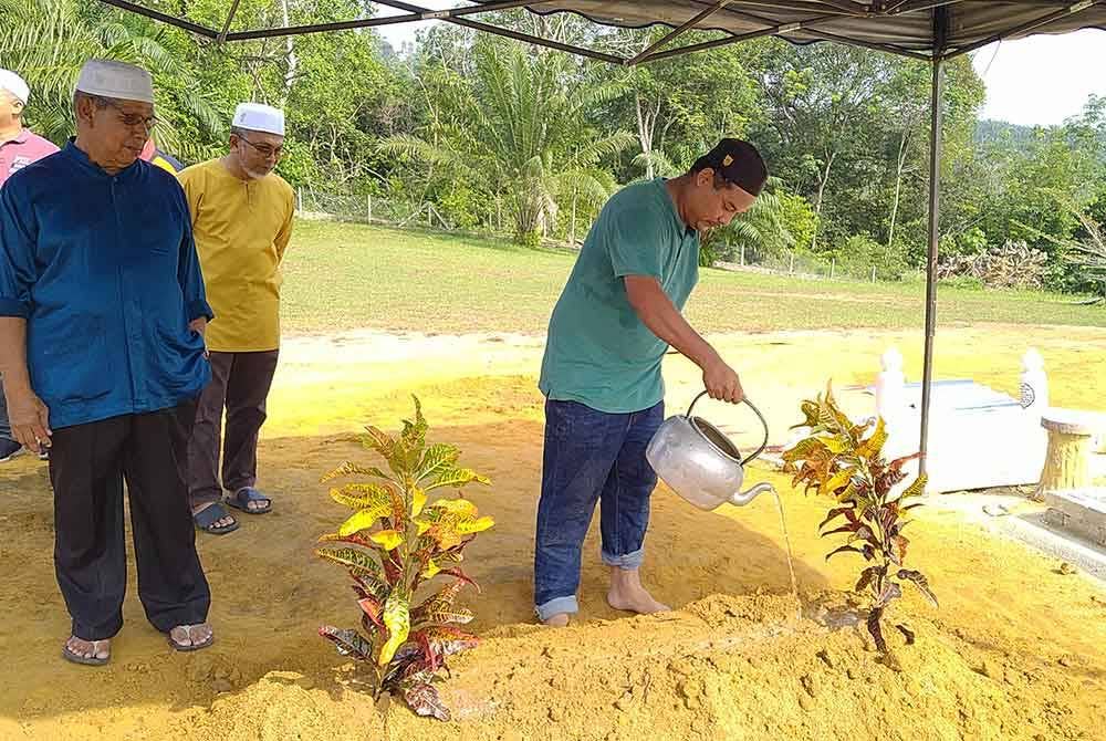 Abu Dzar menyiram air ke pusara bapanya.