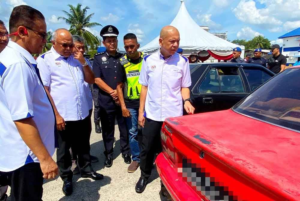 Azman (kiri) menunjukkan kepada Armizan (kanan) kereta-kereta yang dirampas oleh KPDN Kelantan dalam membanteras penyeludupan bahan api.
