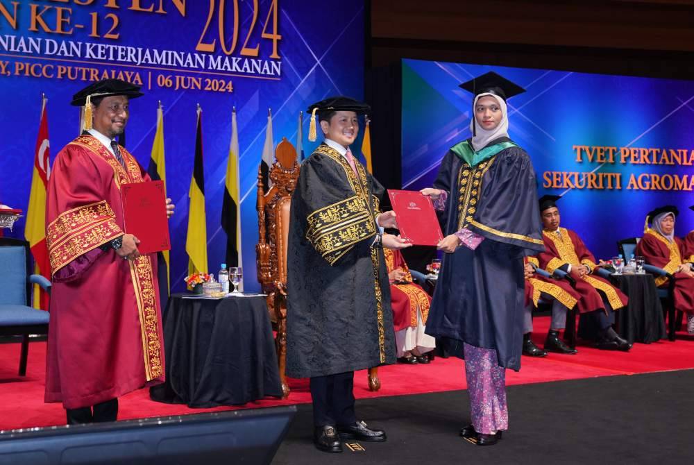 Arthur menyampaikan sijil kepada seorang graduan diploma.