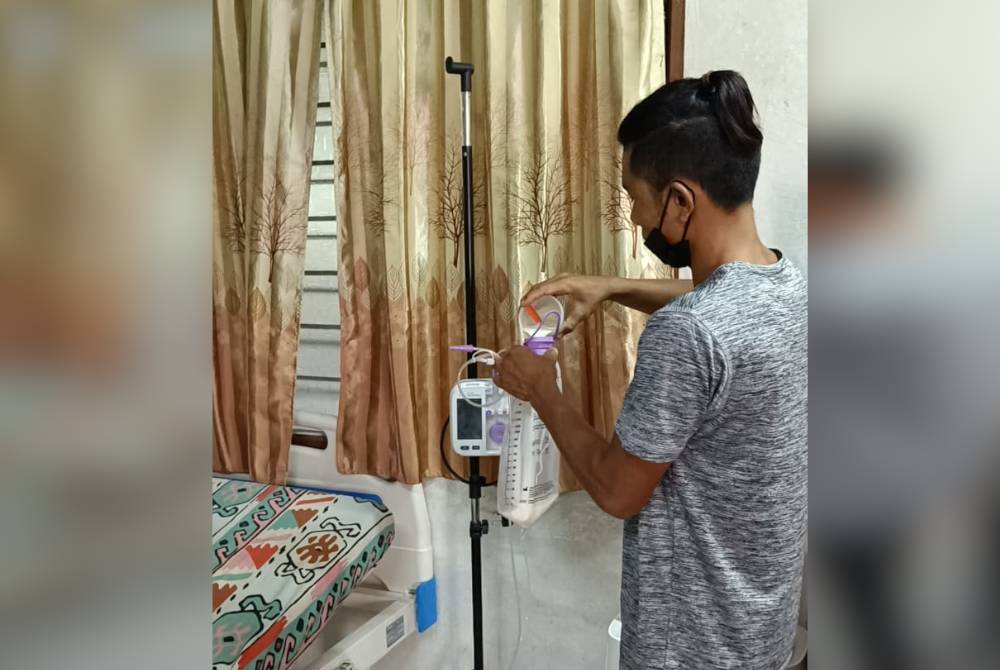 Khairul Azhar membancuh susu untuk dimasukkan dalam saluran tiub itu.