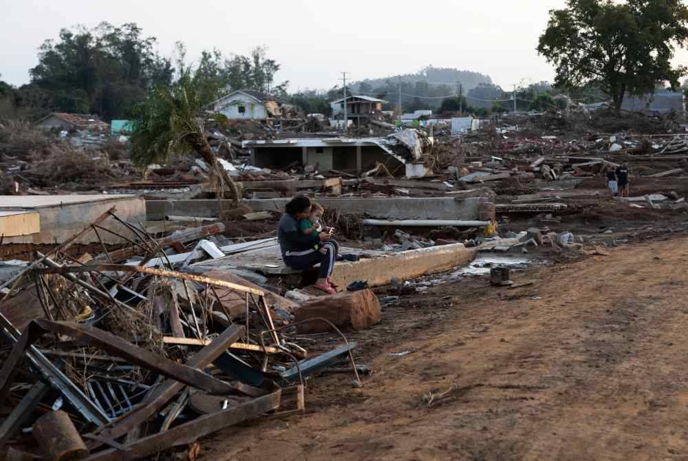 Seorang wanita sedang duduk dengan bayinya atas rumah mereka yang musnah di kejiranan Passo de Estrela Cruzeiro do Sul, Brazil. AFP